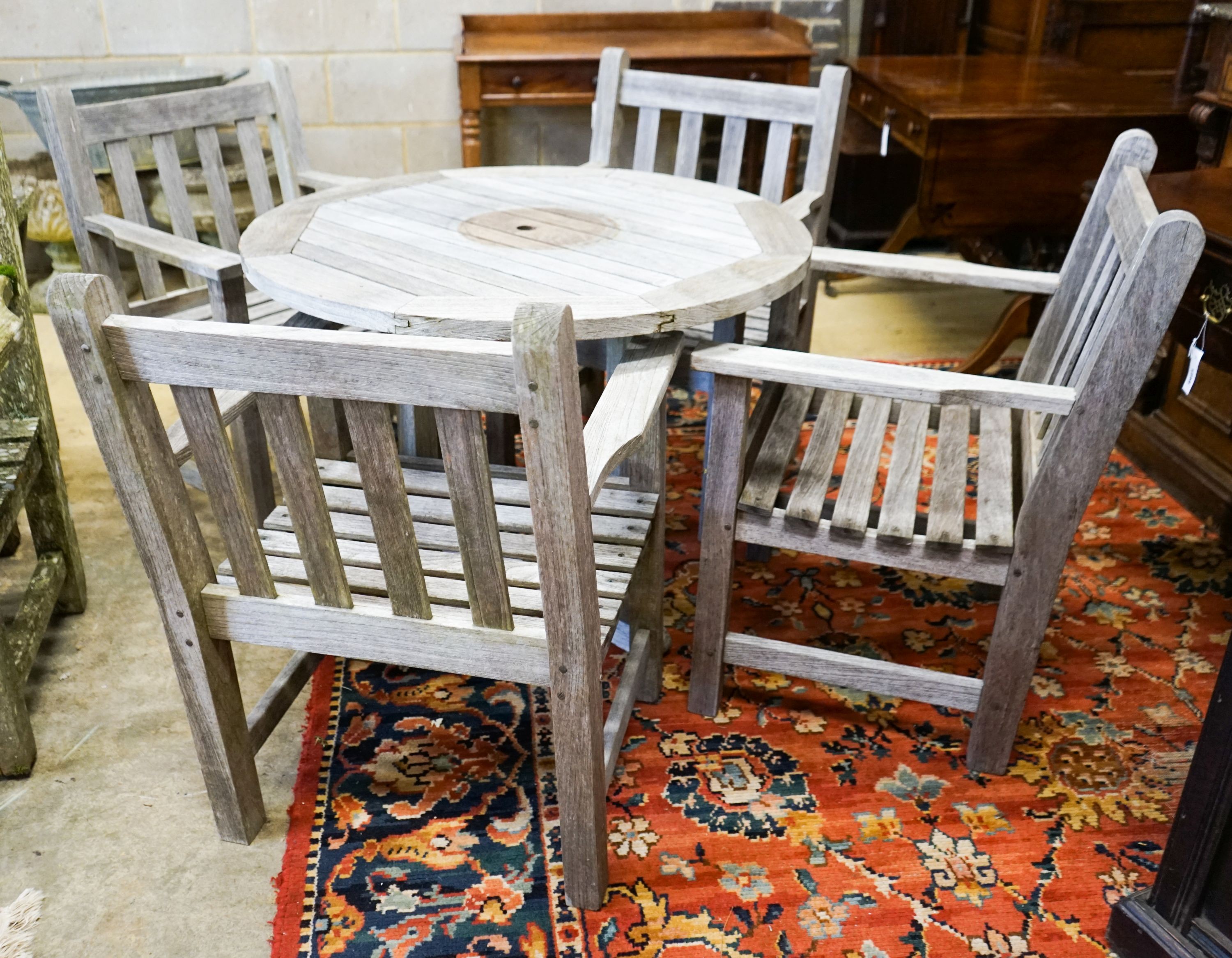 A set of four teak garden chairs and a circular parasol table, diameter 91cm chairs width 60cm